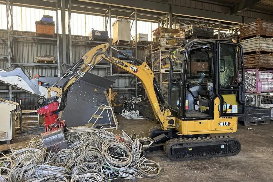 Bagger beim Umsetzen von Kabelschrott in der Halle